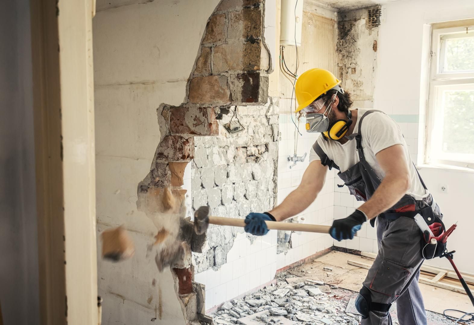 Employé de FLTECk sur un chantier de démolition résidentielle, massue à la main.